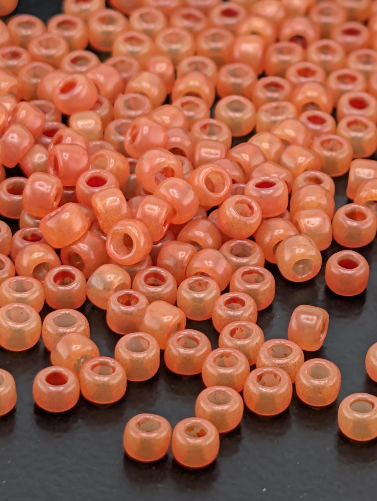 a large number of small, round, orange beads scattered across a dark surface.