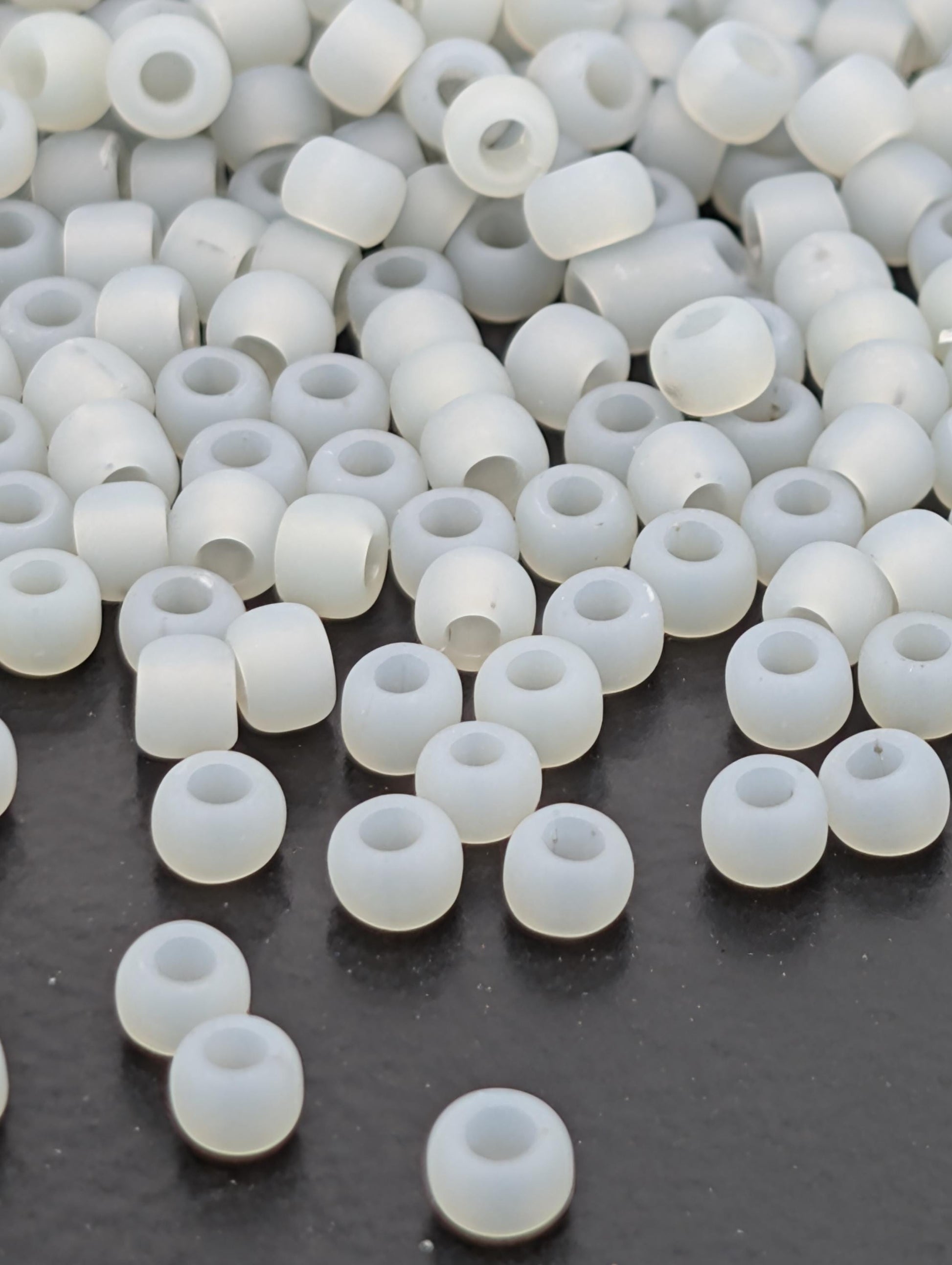 a collection of white, round beads scattered on a dark surface.