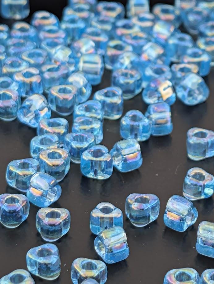 a collection of small, clear blue beads scattered across a dark surface.