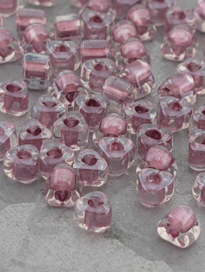 a collection of clear glass beads in various shades of pink, scattered across a surface.