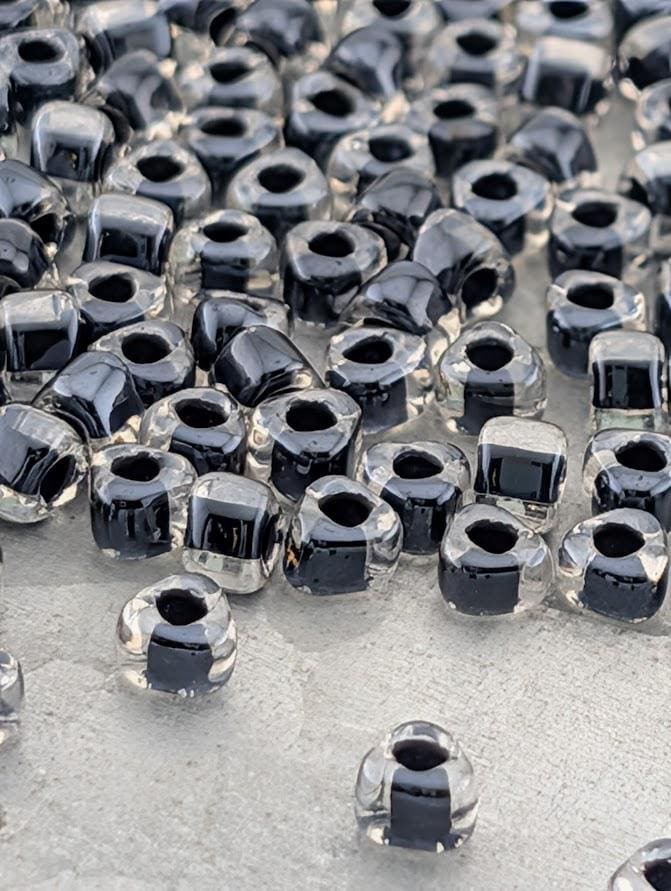 a collection of clear glass beads scattered across a surface, with some of the beads appearing to be black.