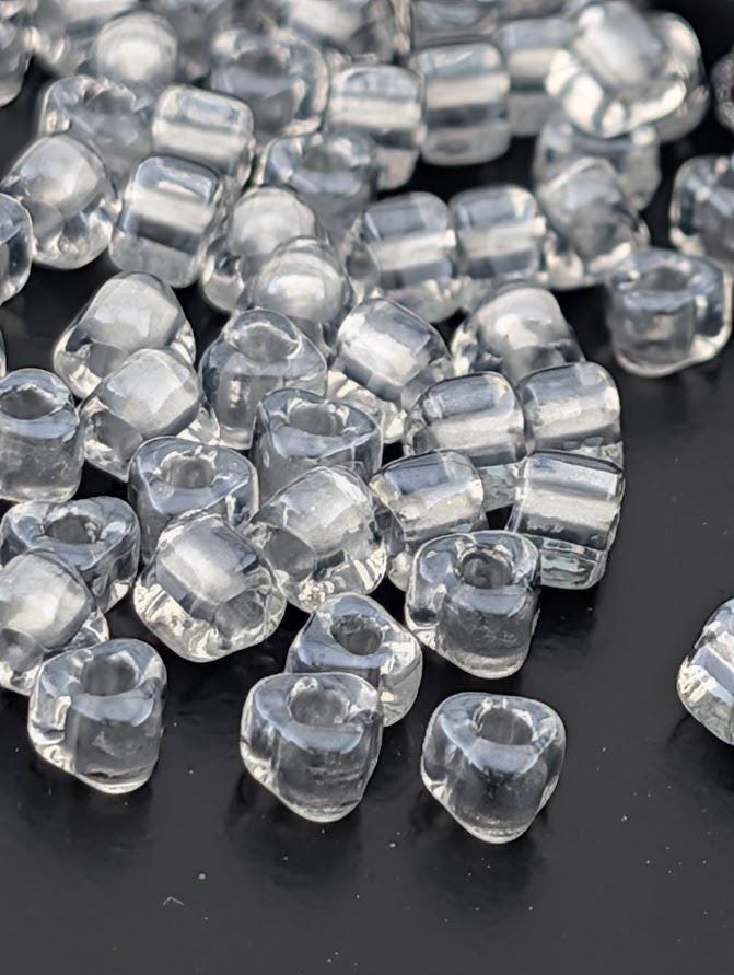 a collection of clear, transparent beads scattered on a dark surface.