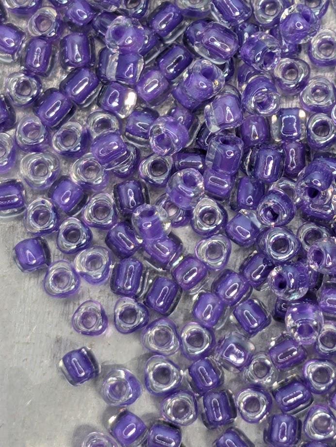 a collection of small, clear beads in shades of purple and white, scattered across a surface.