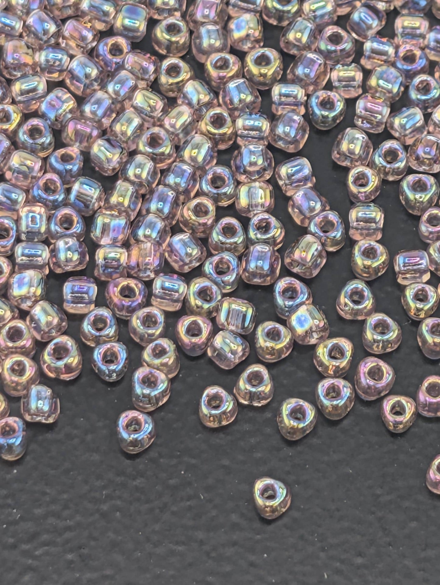 a collection of small, clear beads scattered on a dark surface.