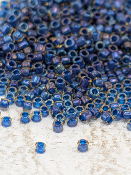 a large pile of blue and gold beads scattered on a white surface.