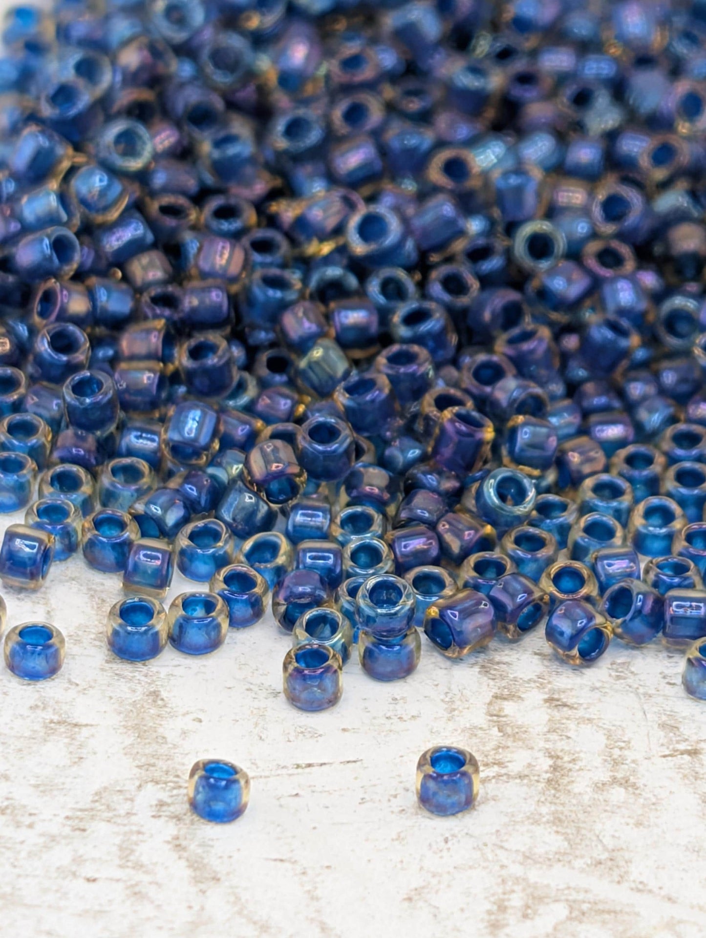 a large pile of blue and gold beads scattered on a white surface.