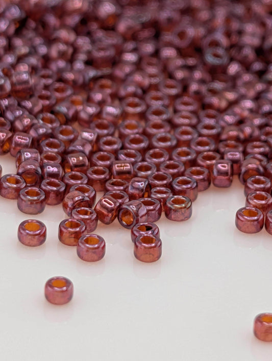 a large number of small, round beads in a variety of colors, including shades of red and orange, scattered across a white surface.