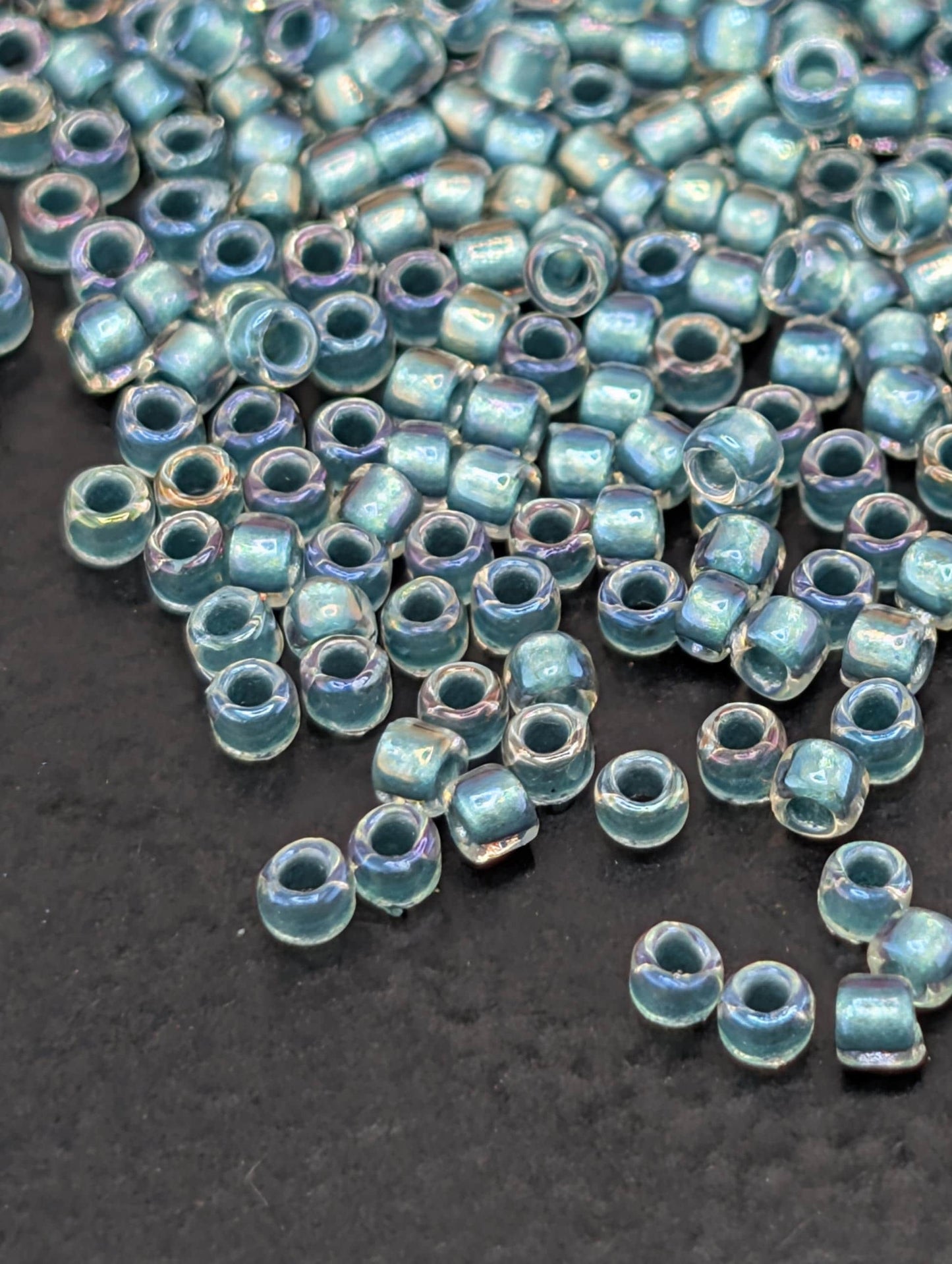 a collection of small, clear beads scattered on a dark surface.