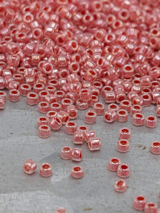 a large pile of small, round, pink beads scattered on a surface.