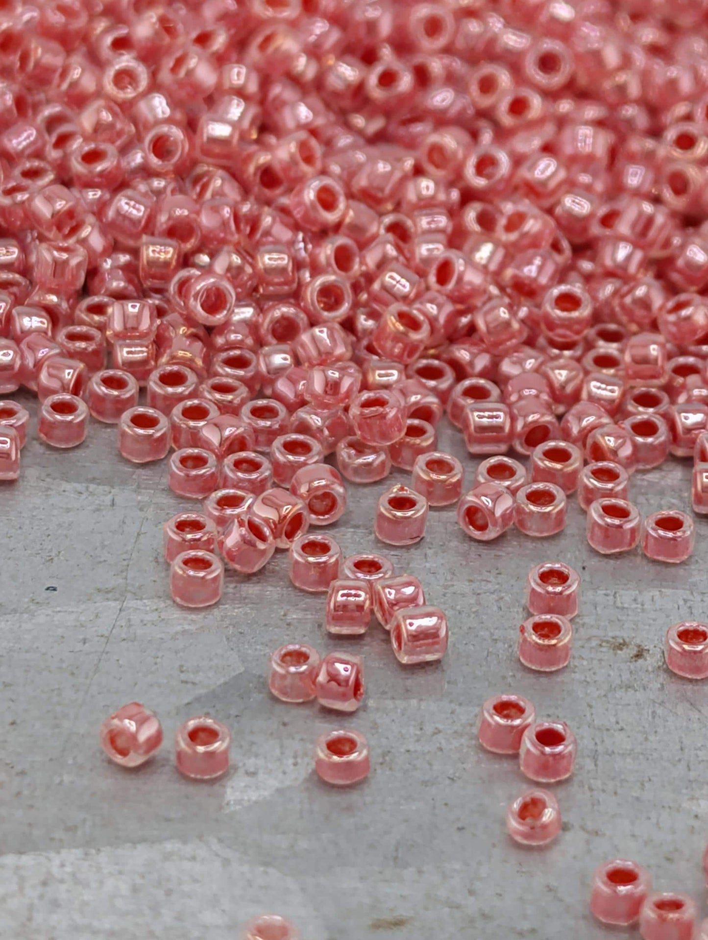 a large pile of small, round, pink beads scattered on a surface.