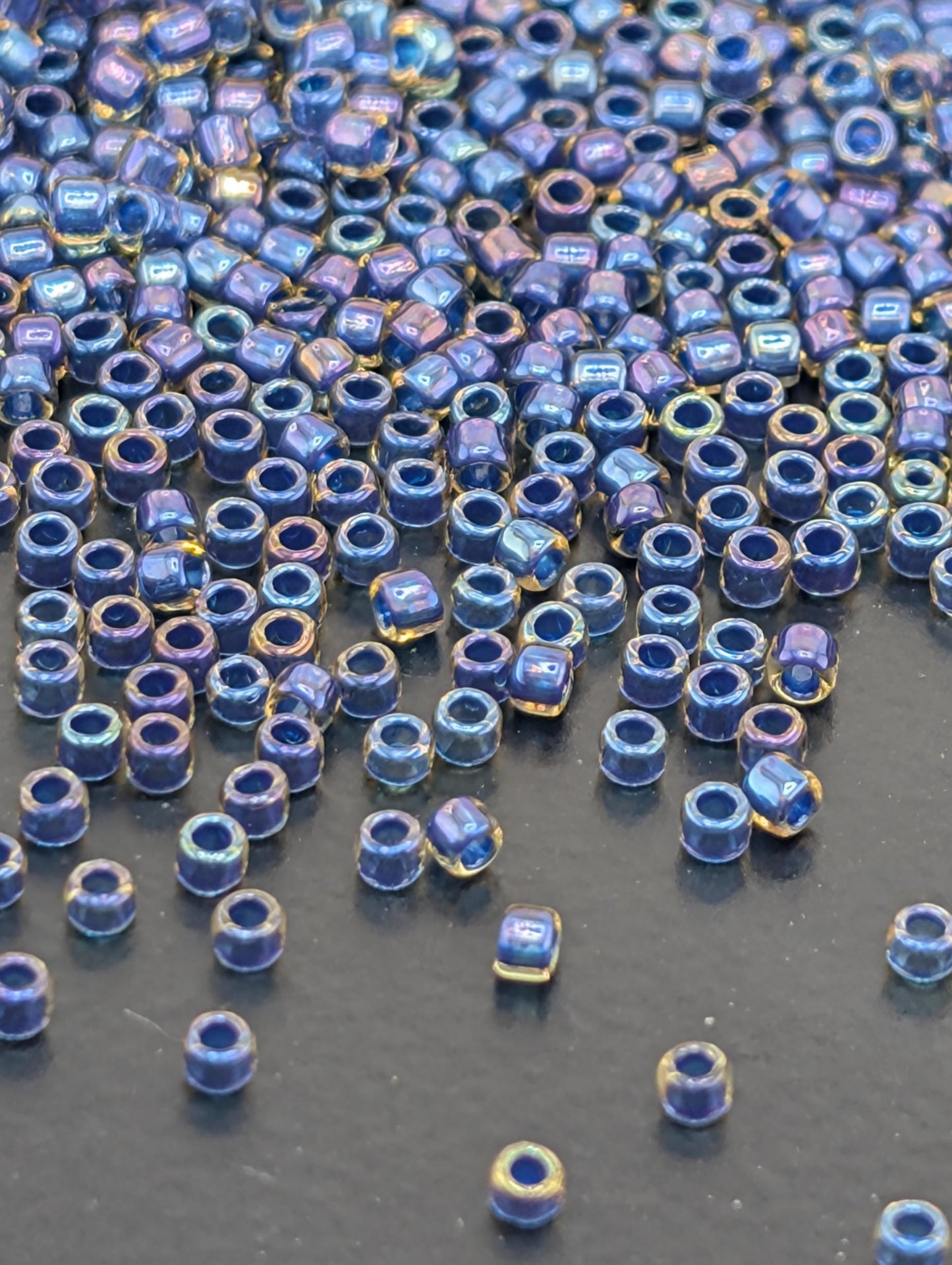 a collection of small, round beads in various shades of blue and gold, scattered across a dark surface.