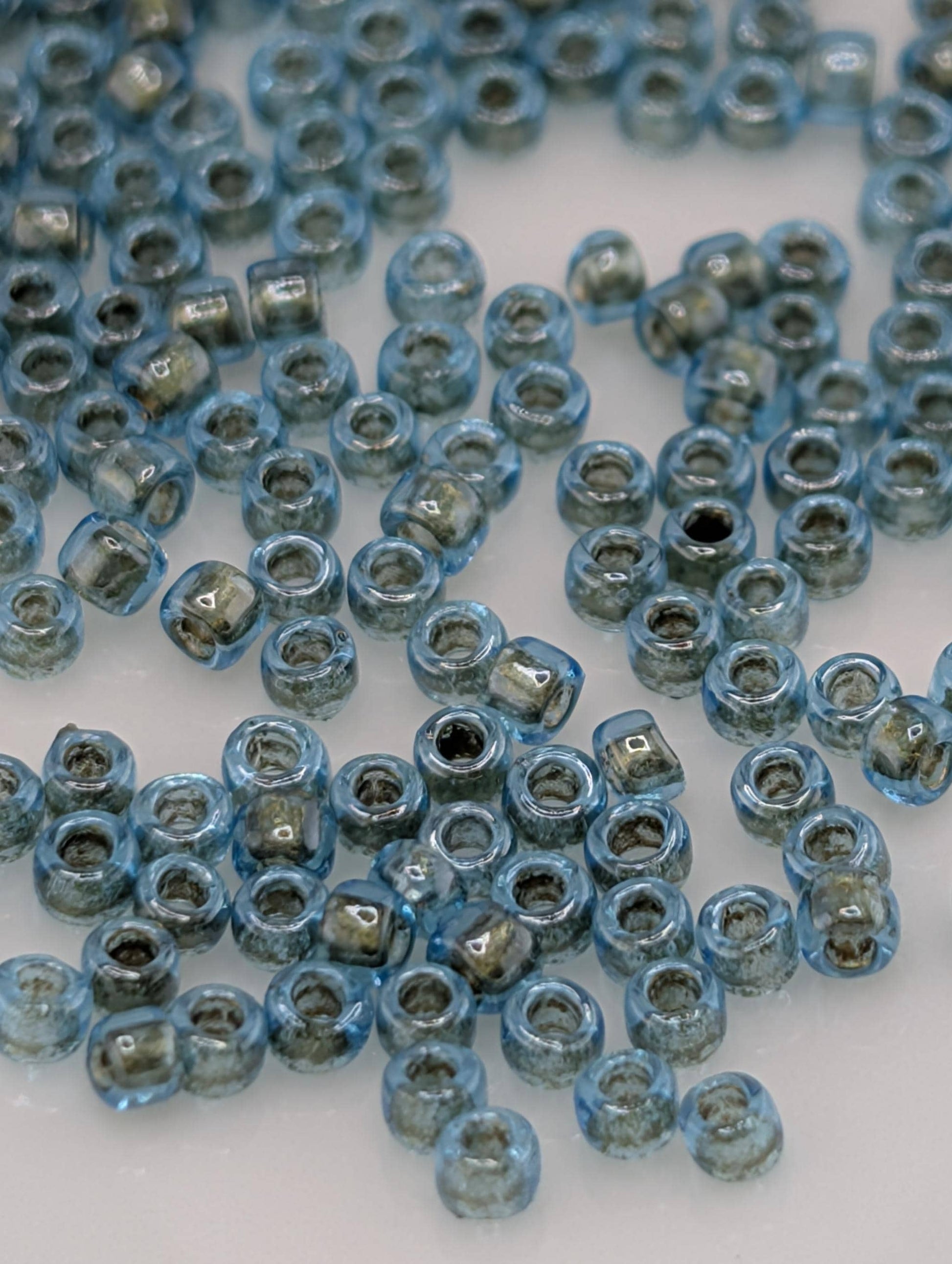 a collection of small, clear beads in various shades of blue, scattered across a white surface.