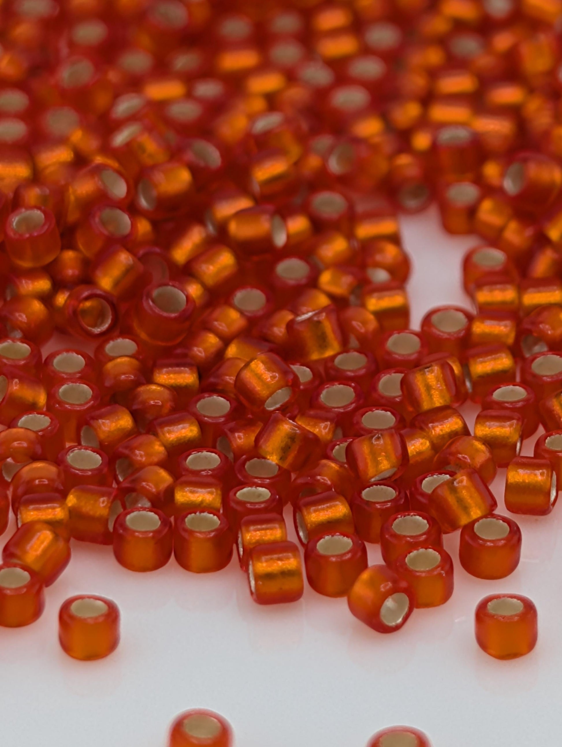 a close-up view of numerous small, round, orange beads scattered across a white surface.