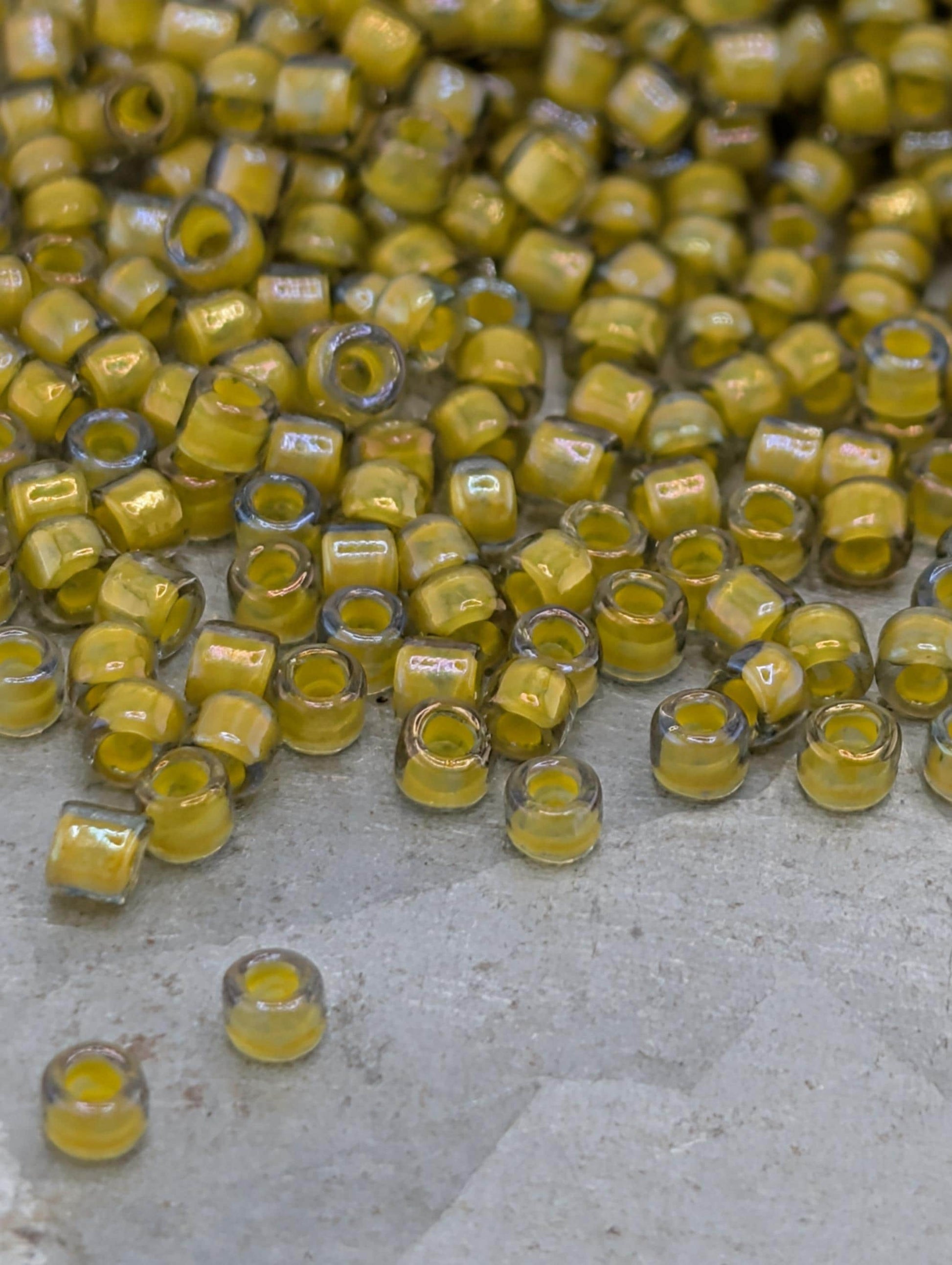 a large pile of yellow glass beads scattered on a surface.