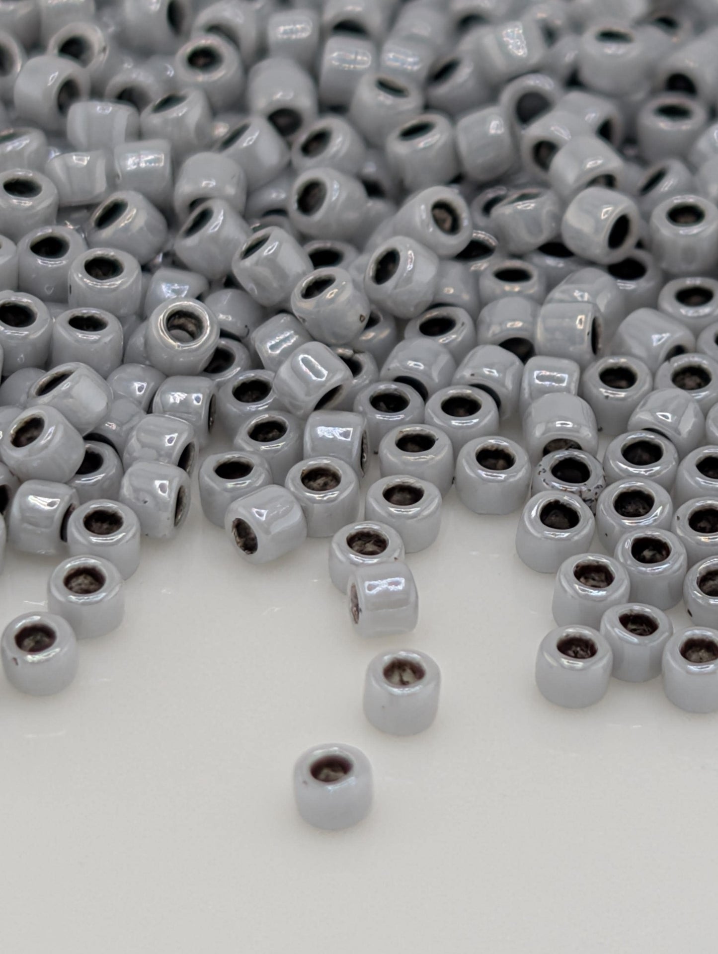 a large pile of small, white beads scattered across a white surface.