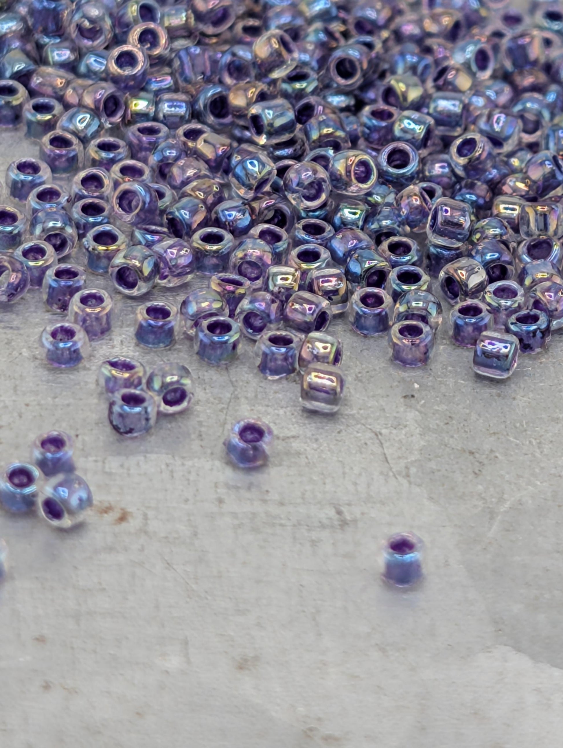 a collection of small, clear beads in various shades of purple scattered across a surface.