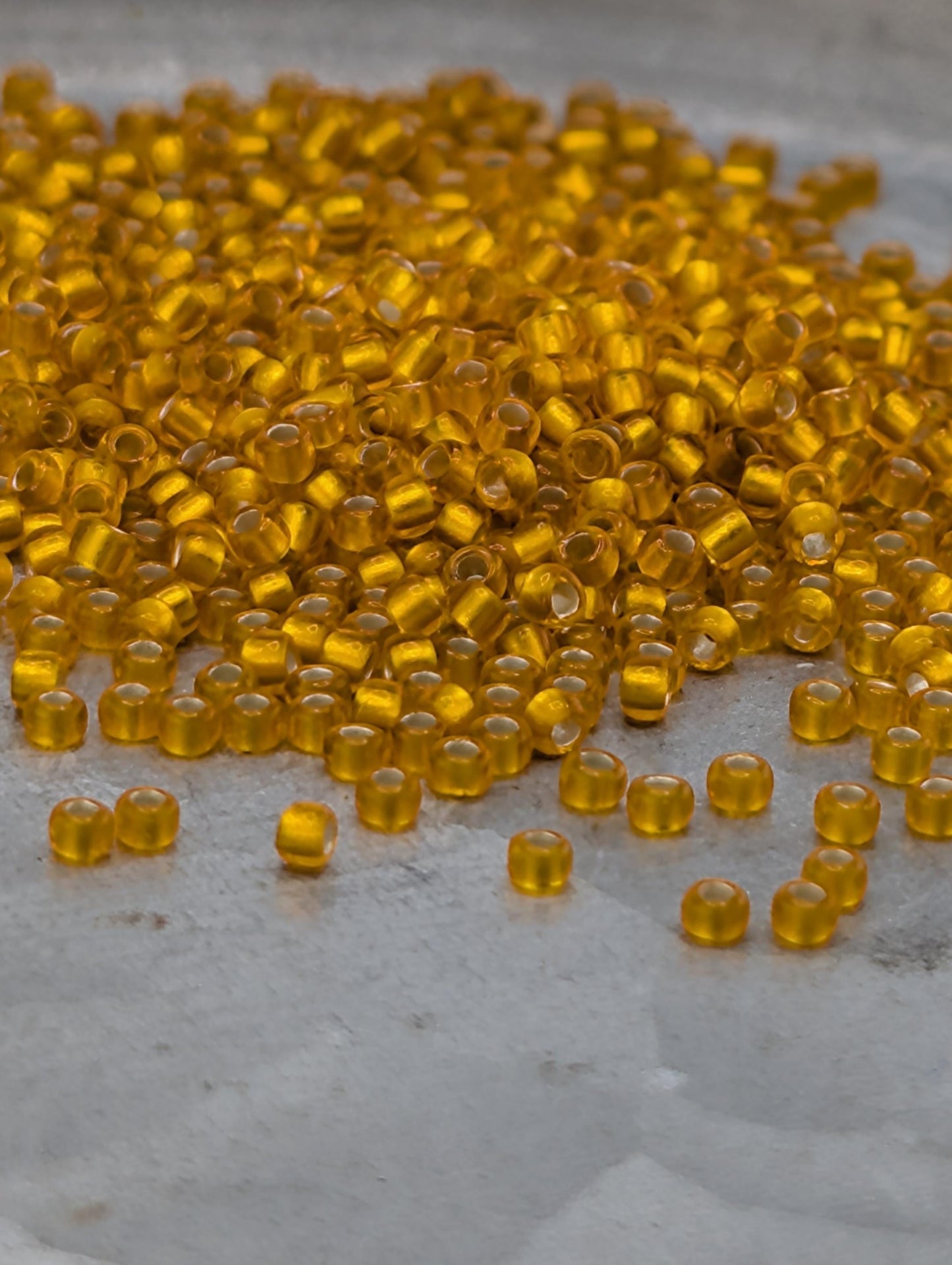 a pile of small, round, yellow beads scattered on a surface.