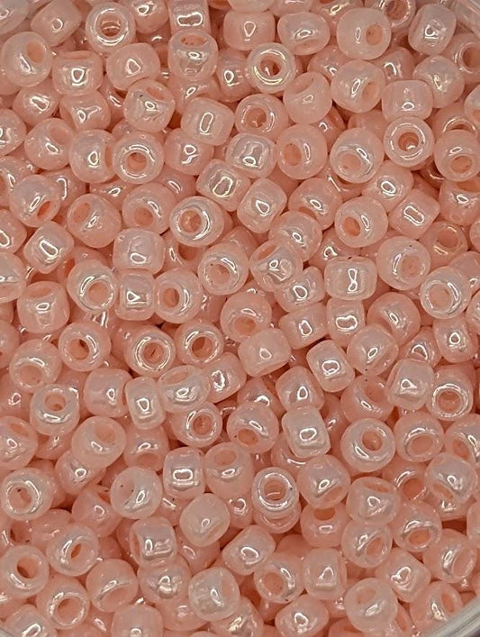 A close-up image of numerous small, clear beads in a light pink color.