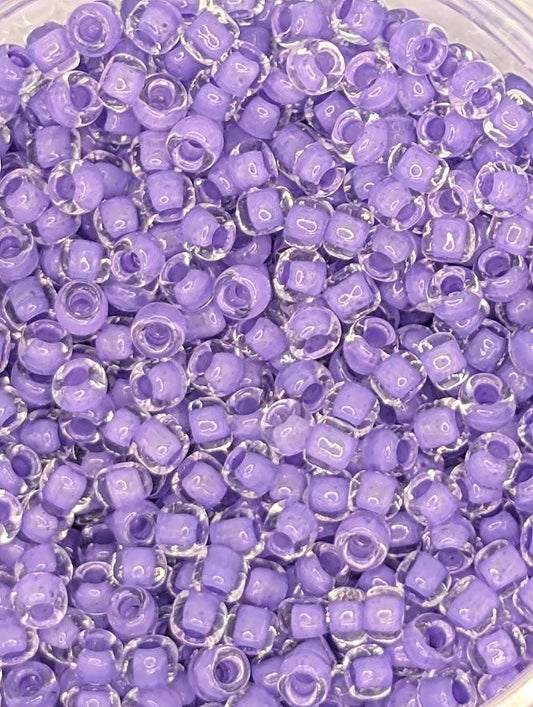 A close-up image of a pile of clear, purple beads or beads with a clear plastic container.