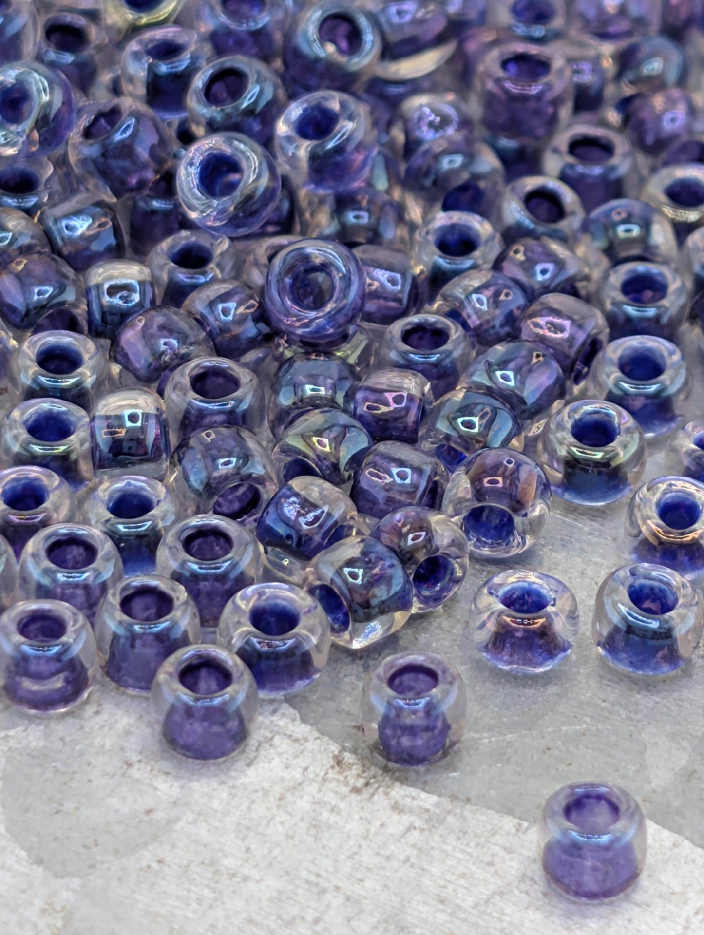 a collection of clear glass beads in various shades of purple, scattered across a surface.