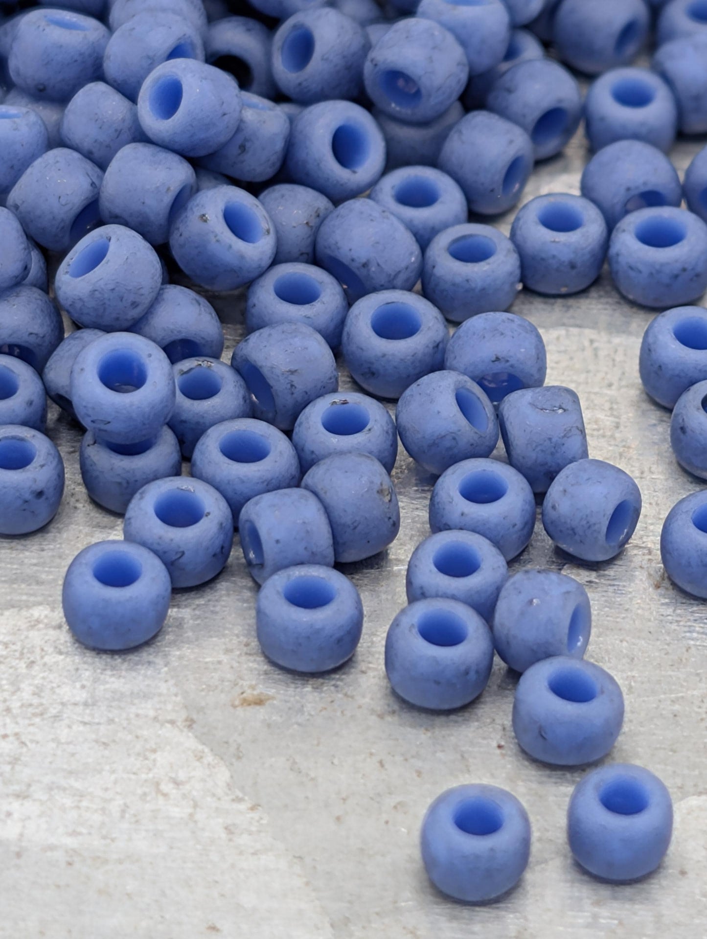 a collection of blue beads scattered on a surface, with some of the beads falling or spilling onto the surface.