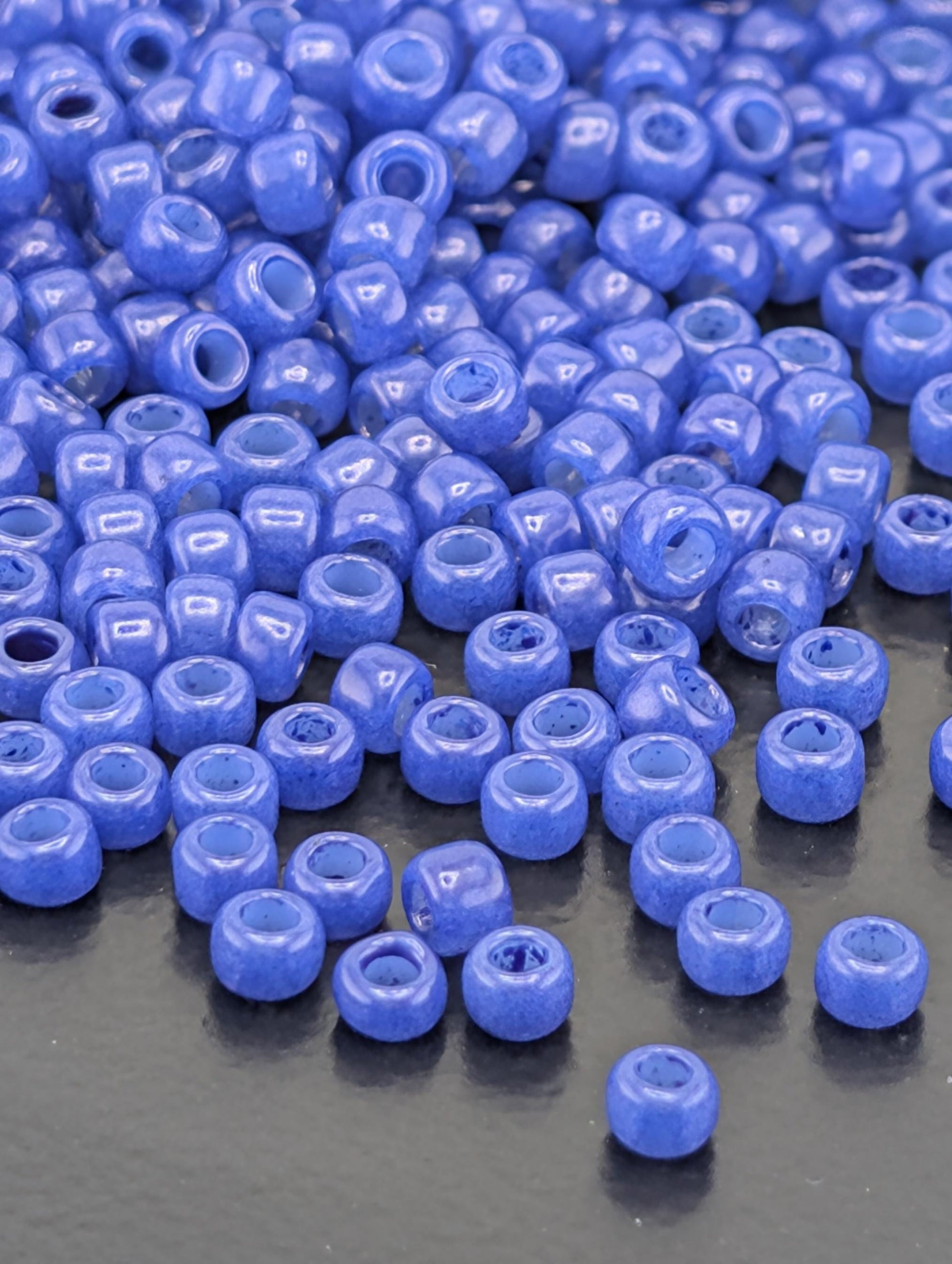 a large pile of small, round, blue beads scattered on a dark surface.
