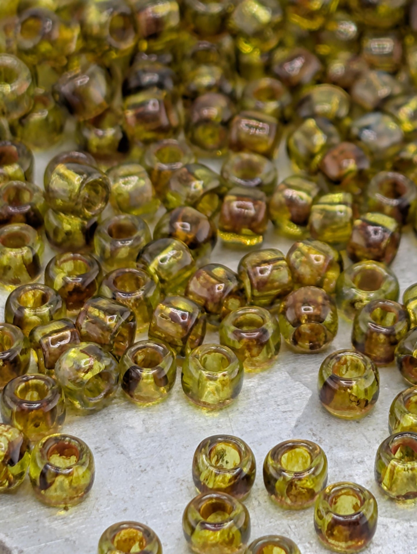 a collection of small, clear glass beads in various shades of green and brown, scattered across a surface.