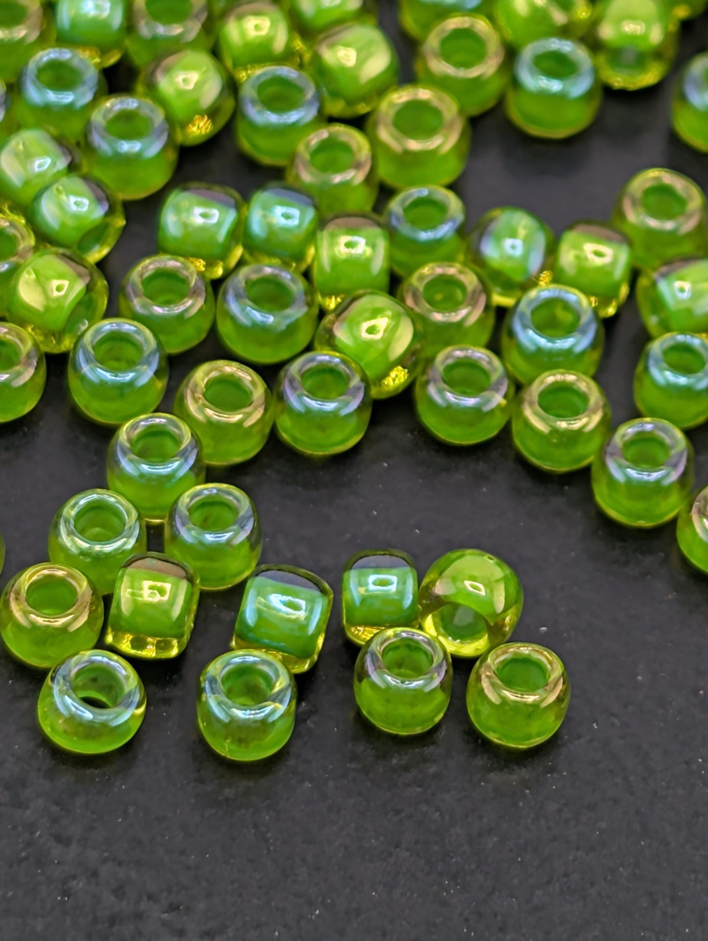 a collection of small, green and yellow glass beads scattered on a dark surface.