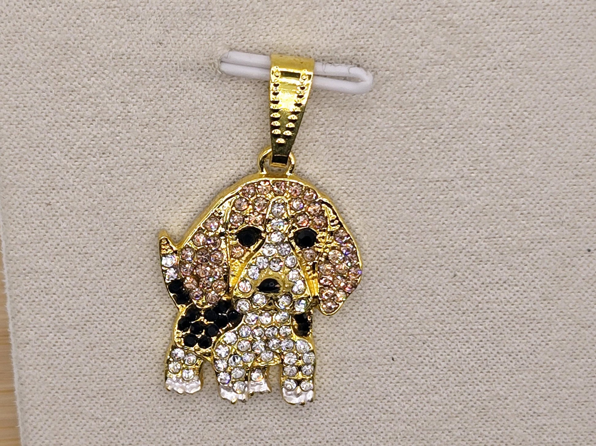 A gold-colored charm in the shape of a dog, adorned with numerous sparkling diamonds.