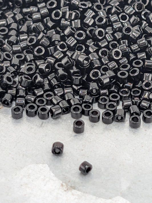 a large pile of black beads or nuts scattered on a white surface.