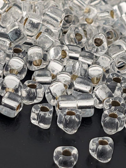 a collection of clear glass beads scattered on a dark surface.