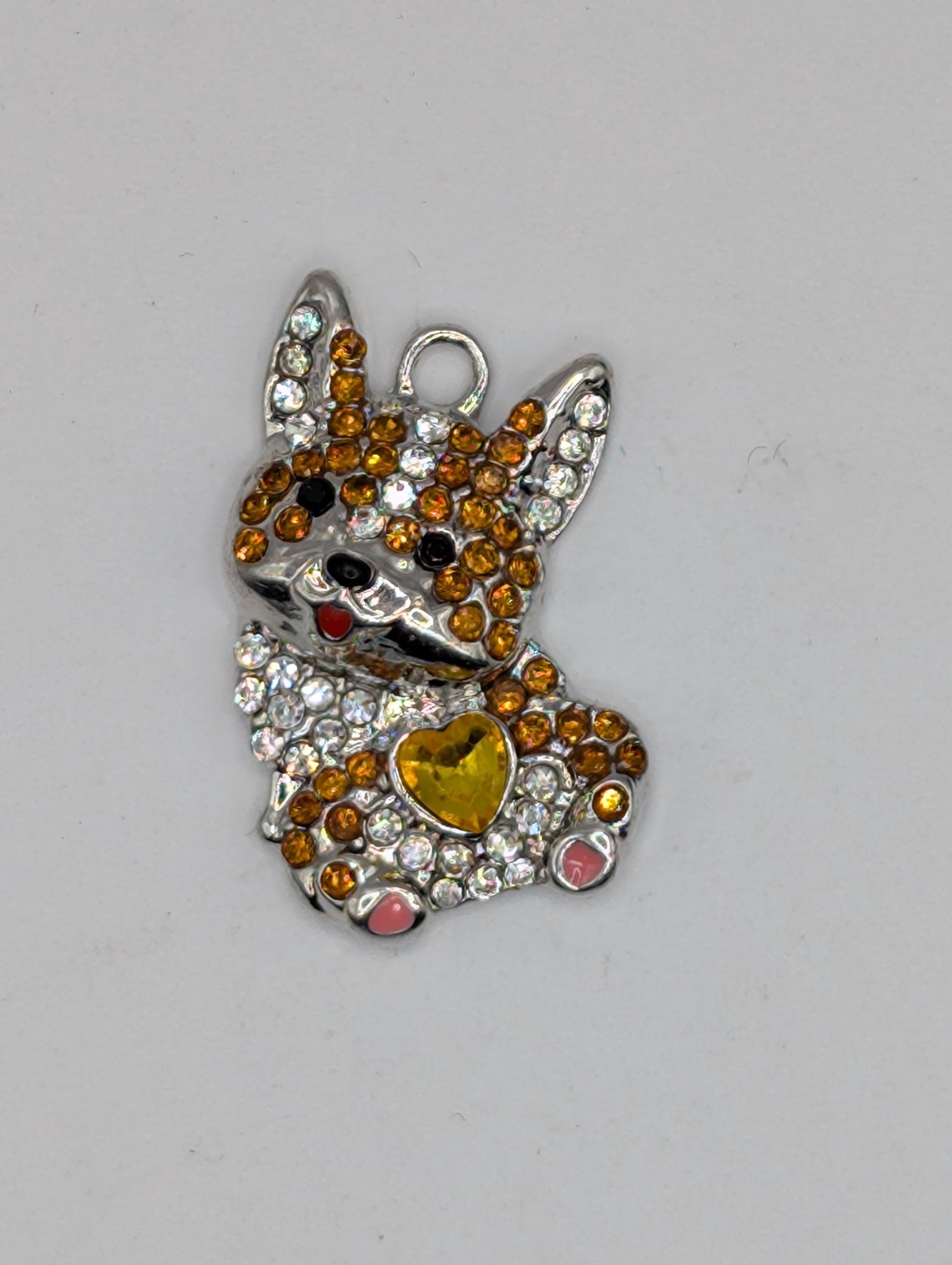 A decorative piece featuring a combination of colorful gemstones and metallic elements, such as a heart-shaped accent and a metallic clasp.