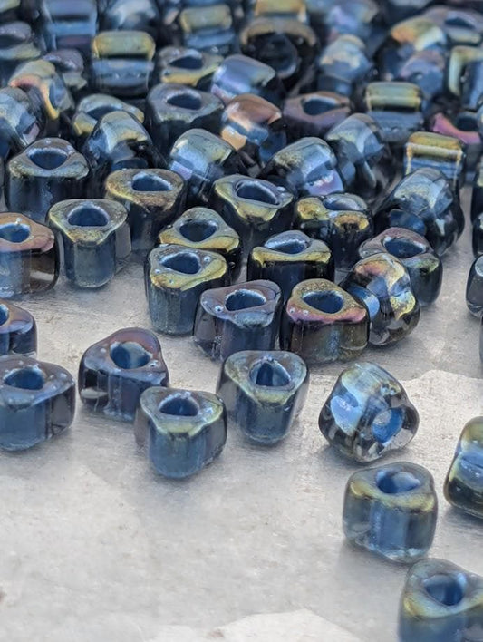 a collection of small, blue glass beads scattered on a surface.