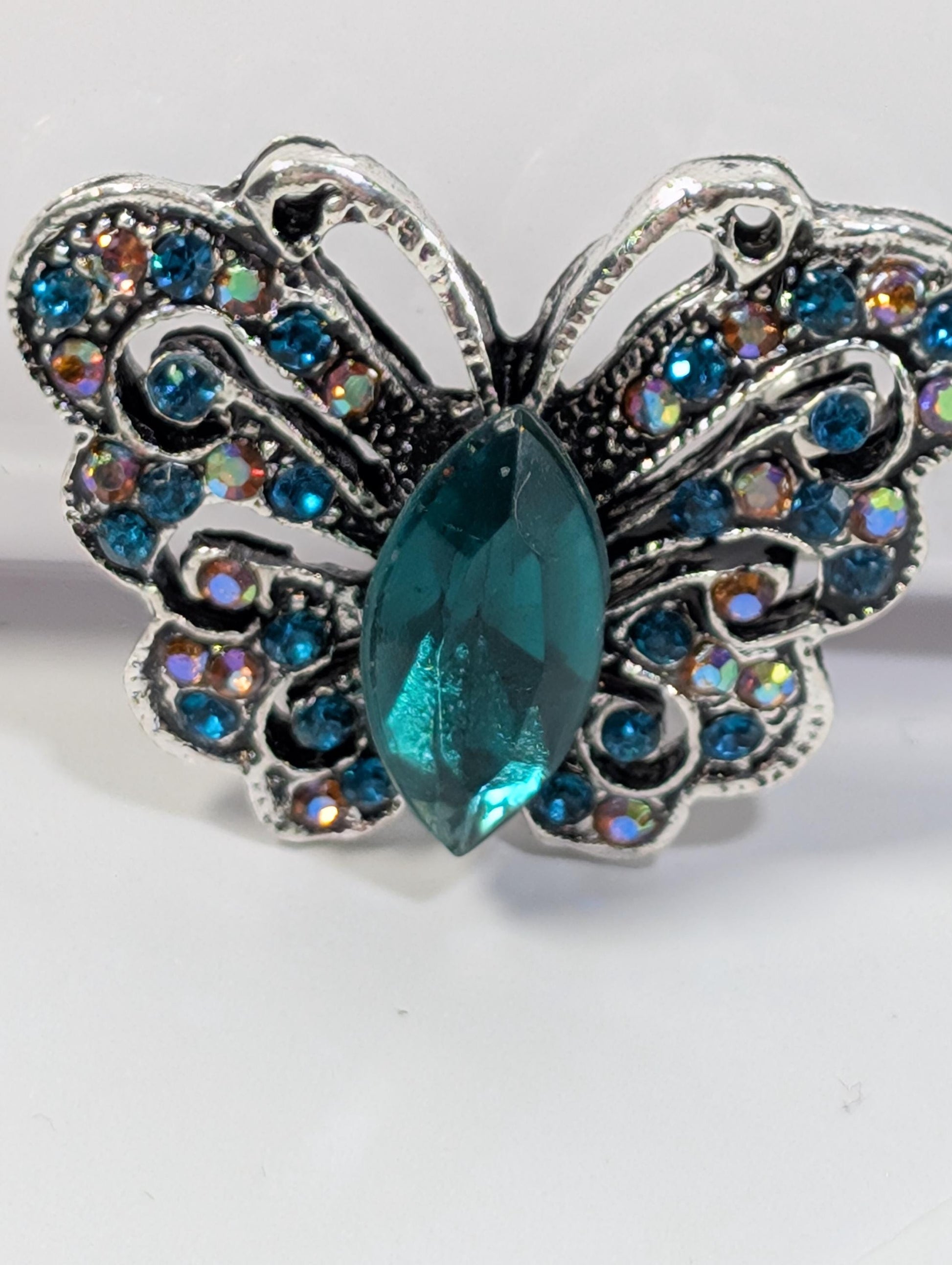 A silver butterfly-shaped ring with a large blue gemstone in the center.