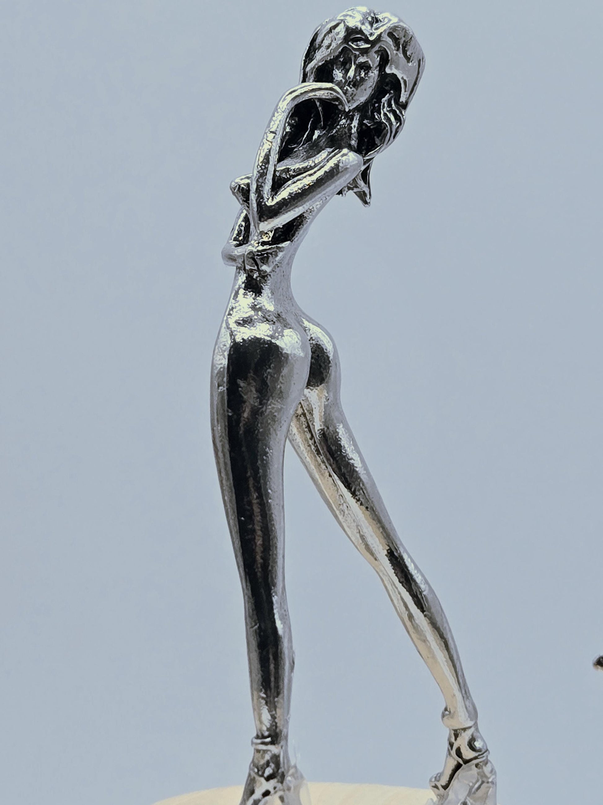 A close-up view of a shiny, metallic sculpture of a human figure.