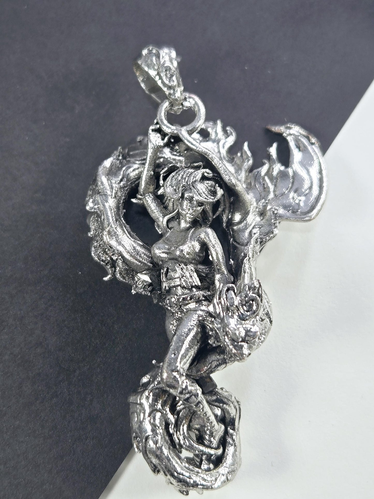 A detailed silver sculpture of a dragon-like creature with intricate, flowing designs and a fierce expression.