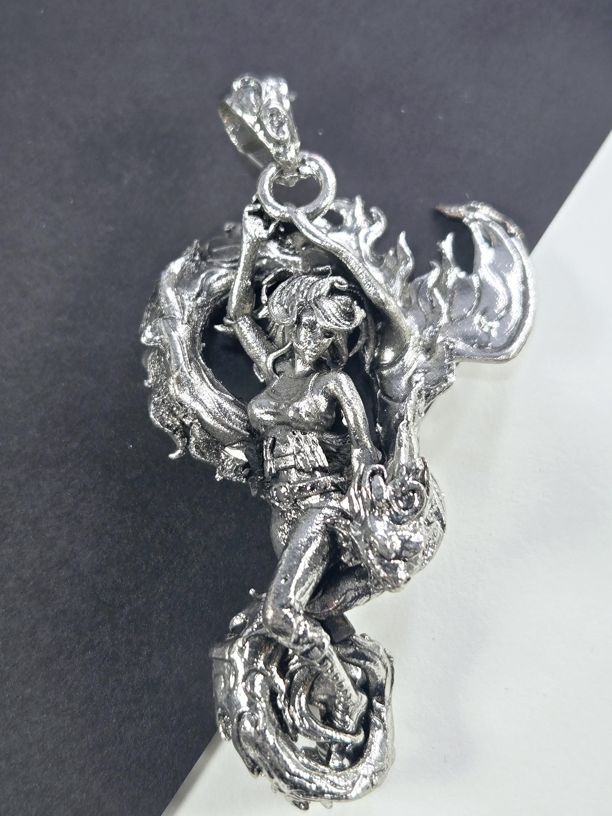 A detailed silver sculpture of a dragon-like creature with intricate, flowing designs and a fierce expression.