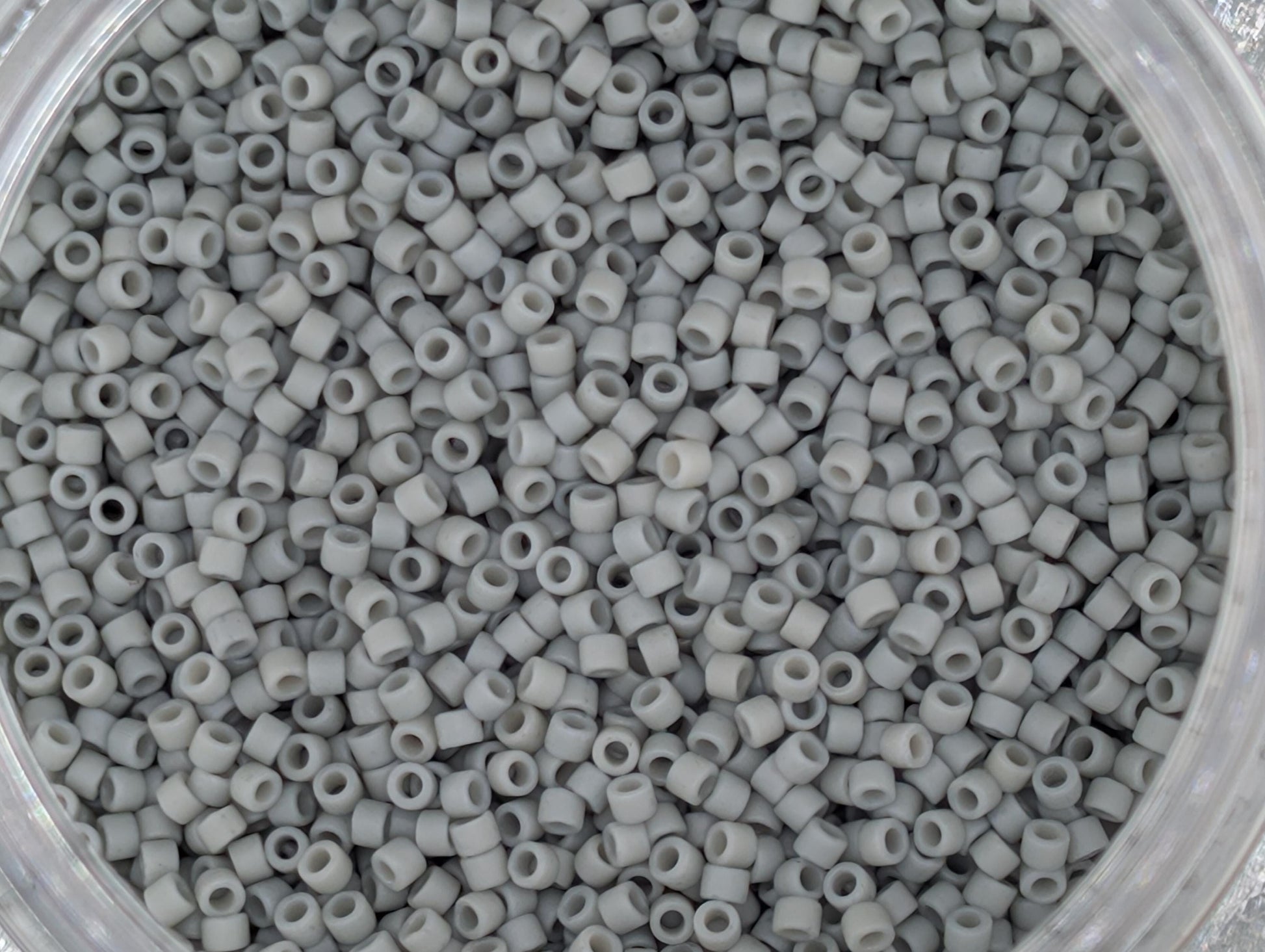 A close-up image of a container filled with small, white beads or plastic beads.