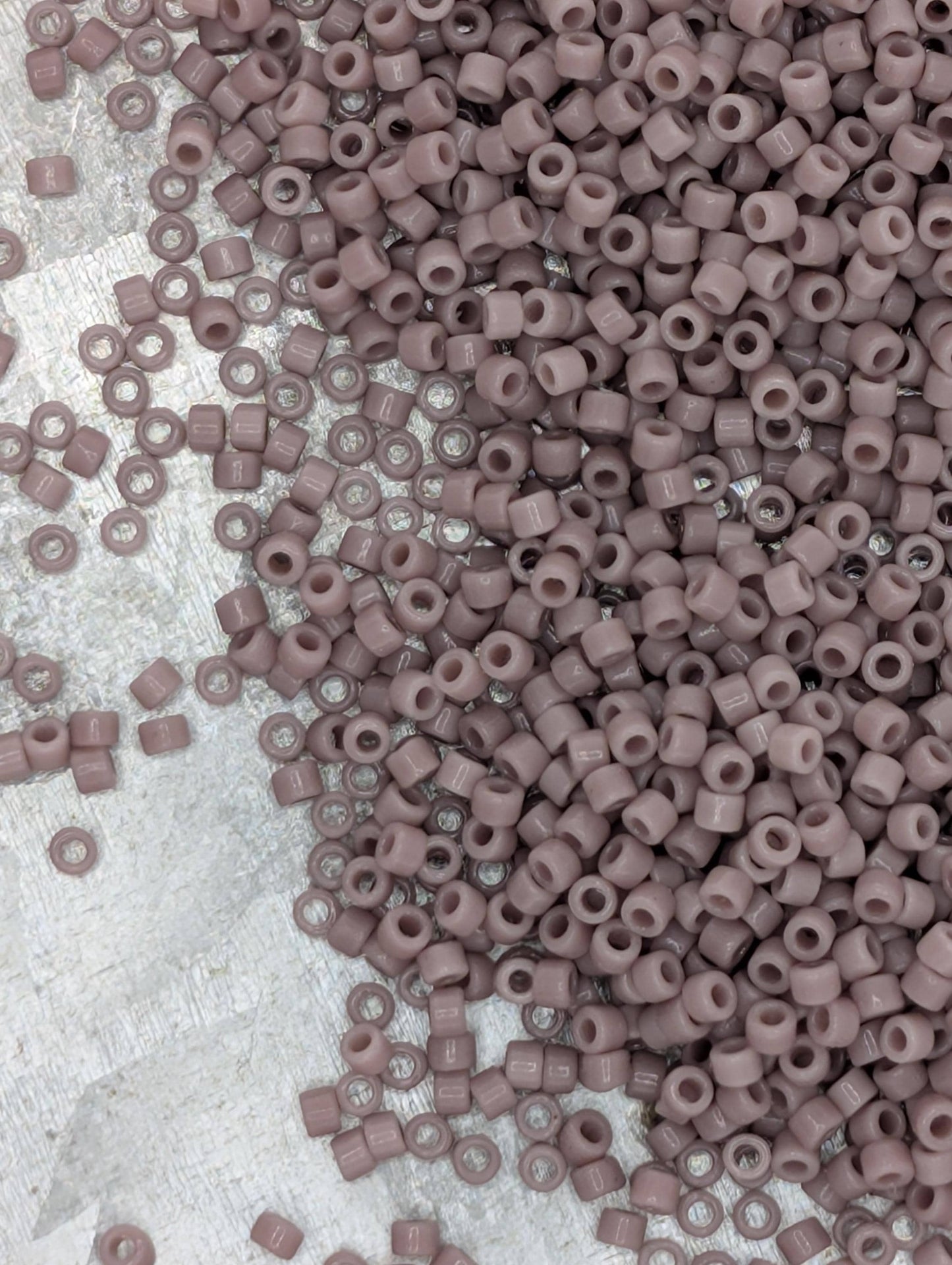 a large pile of small, round beads in various shades of pink, scattered across a surface.