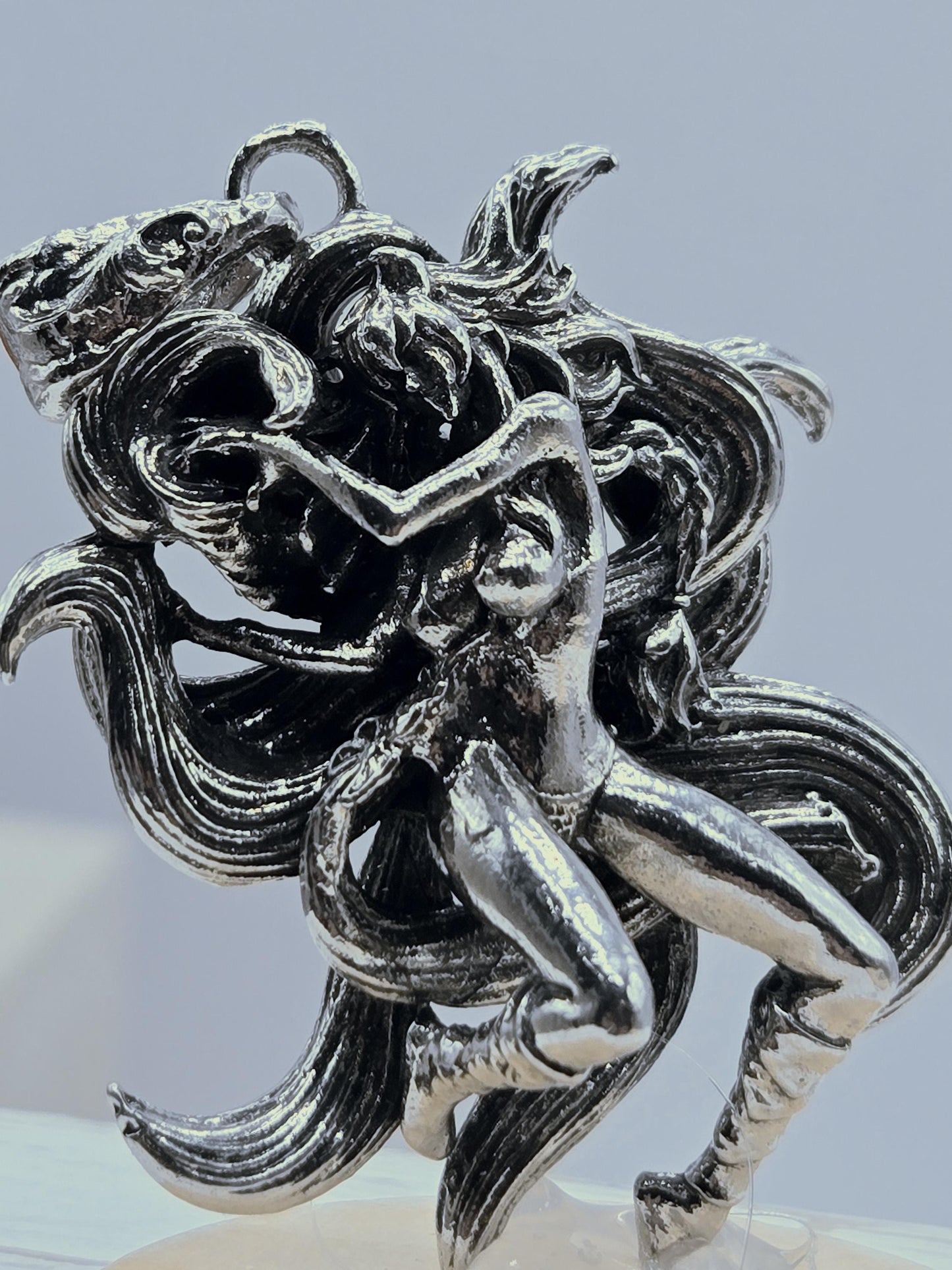 a silver-colored metal sculpture of a woman with flowing hair and an intricate design.