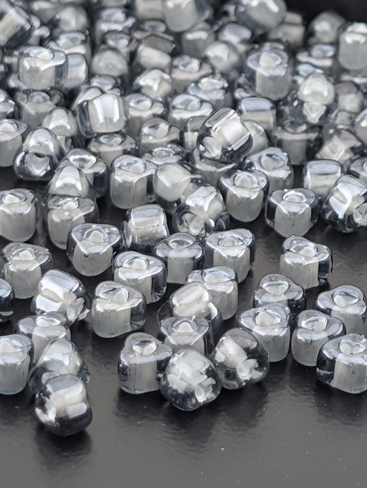 a collection of small, clear glass beads scattered across a dark surface.