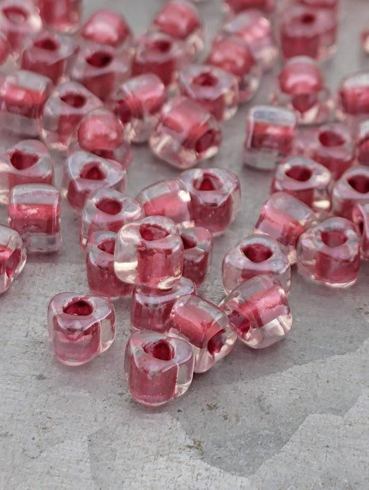 a collection of clear glass beads in various shapes and sizes, scattered on a surface.