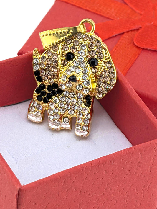 A gold-colored pendant in the shape of a dog, adorned with numerous sparkling diamonds, is displayed in a red gift box.