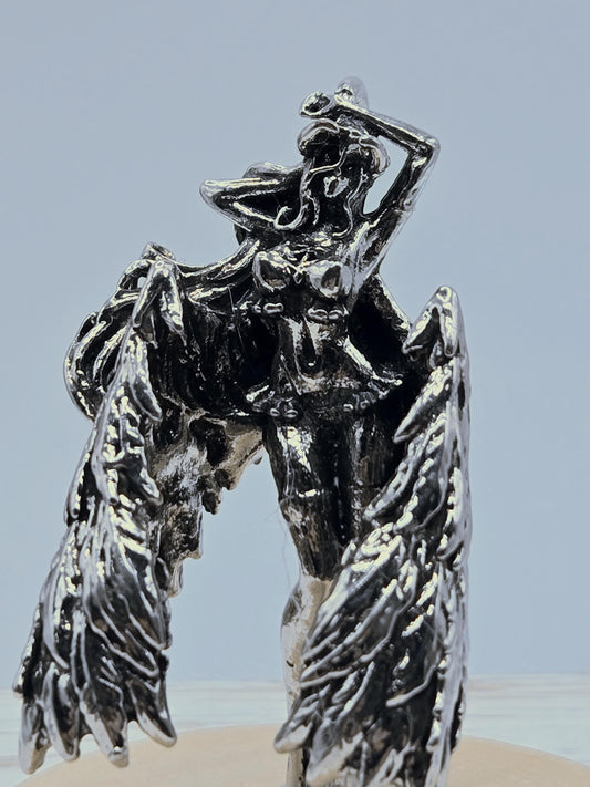 A close-up view of a shiny, metallic sculpture with a wing-like design, possibly resembling a bird or angel figure.