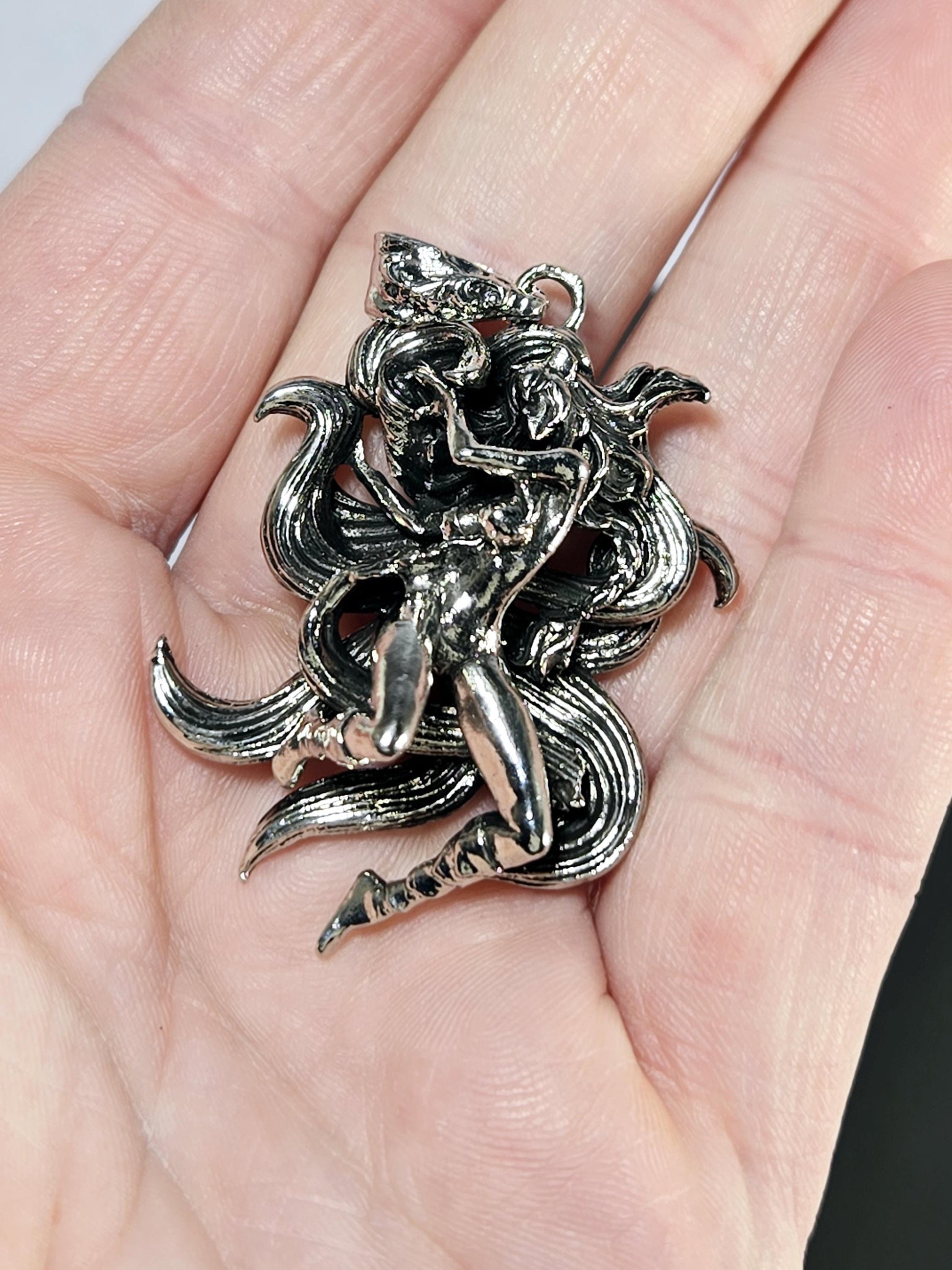 A close-up image of a person&#39;s hand holding a silver, intricately designed metal piece, which appears to be a decorative piece or a piece of jewelry.