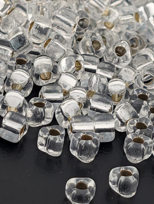 a collection of clear glass beads scattered on a dark surface.