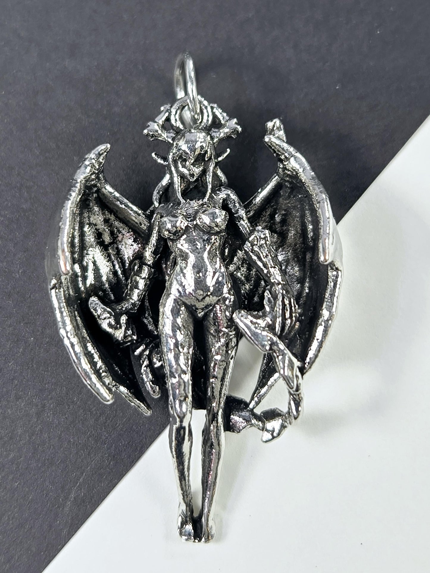 A silver-colored metal sculpture depicting a winged, armored figure with a fierce expression.