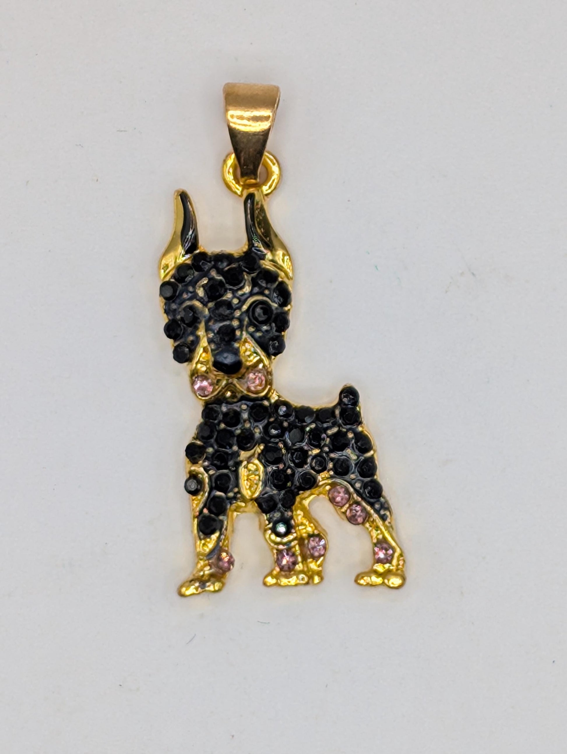 A gold-colored pendant in the shape of a dog, adorned with black gemstones.