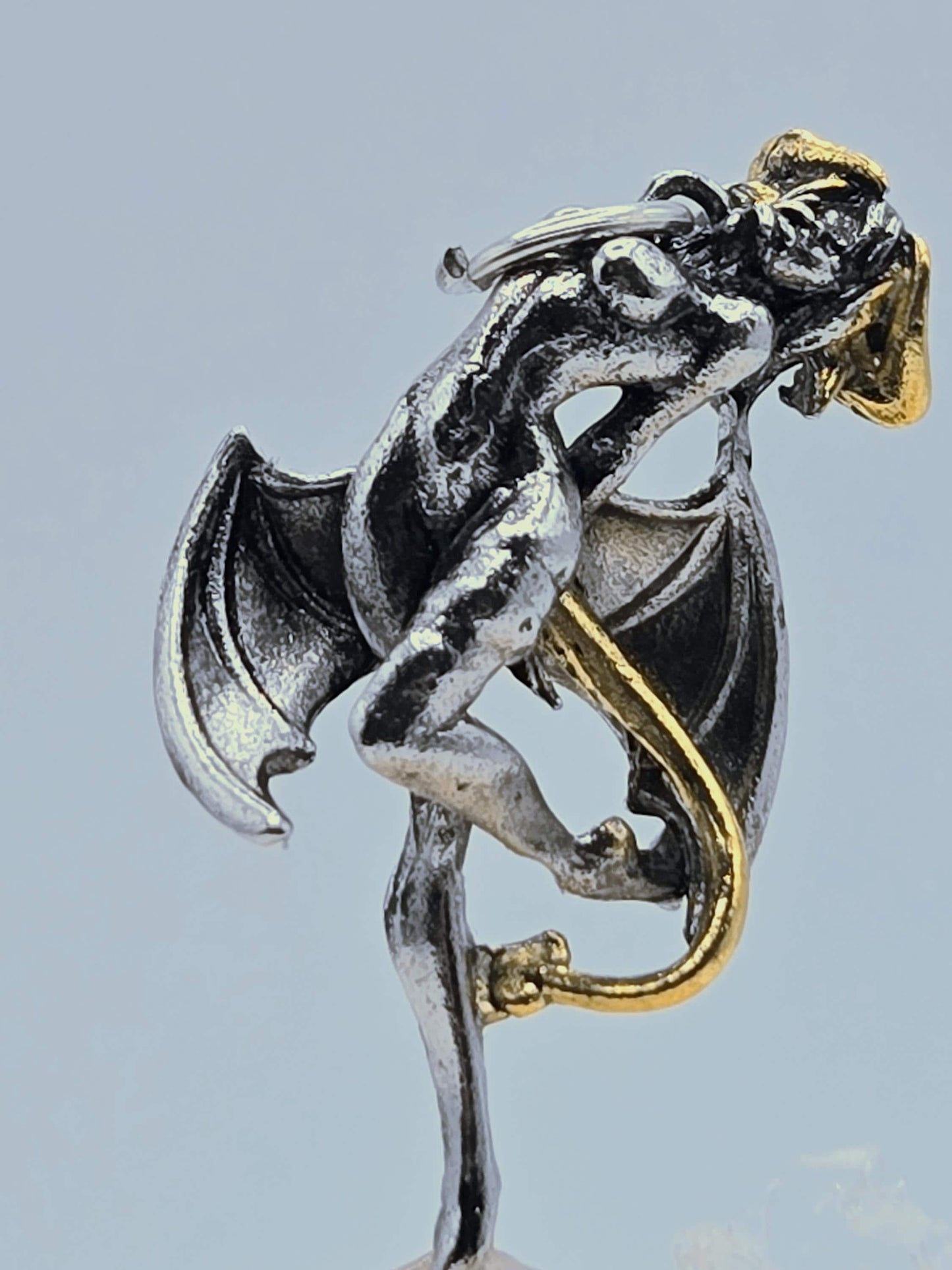 A metallic sculpture of a winged, winged creature with a human-like body and a metallic bat-like wing.