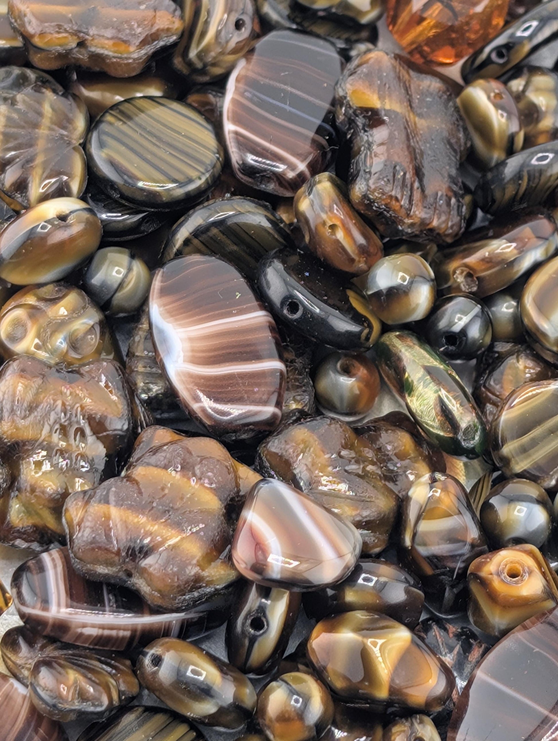 a close-up view of various colored beads and stones, including black, brown, and orange, scattered together.